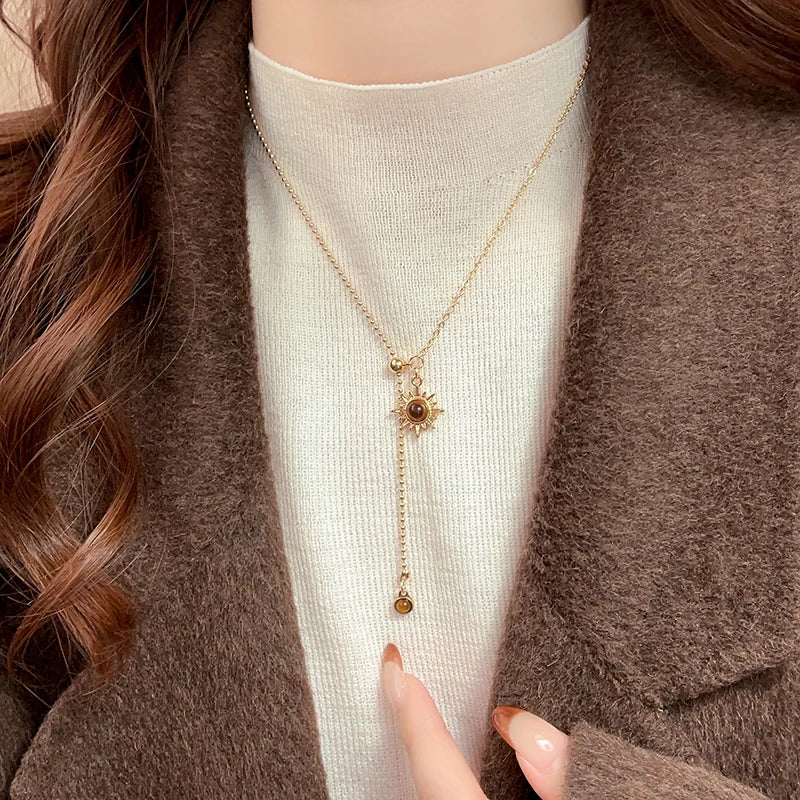 Tie necklace with sunburst charms and tiger's eye stones