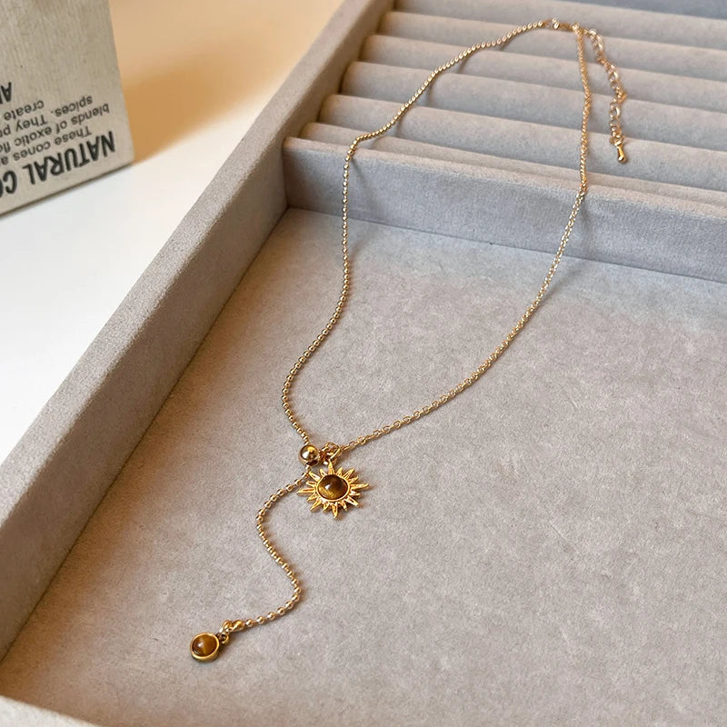 Tie necklace with sunburst charms and tiger's eye stones