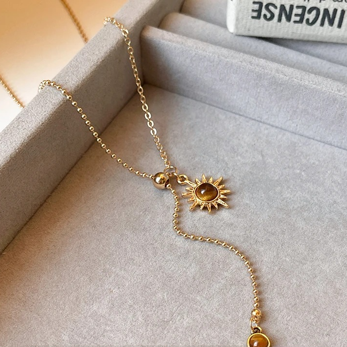 Tie necklace with sunburst charms and tiger's eye stones